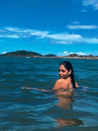 Portrait of woman swimming in sea against blue sky