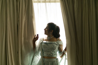 Side view of young woman looking through window