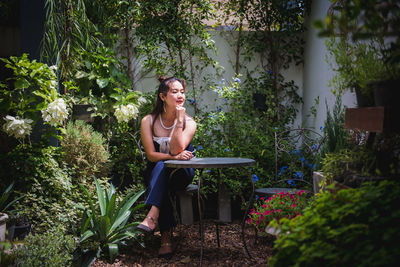 Young woman sitting on plant against trees