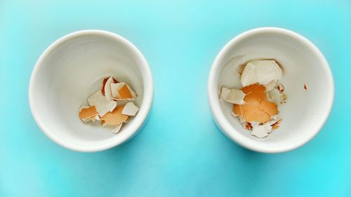 Directly above shot of eggshells in eggcups over colored background