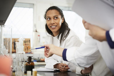 Cropped mature female chemistry teacher explaining to young students in laboratory