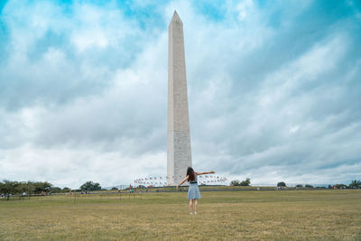 Man standing on field against cloudy sky