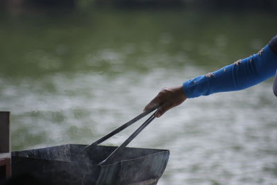 Cropped hand of person preparing food by lake