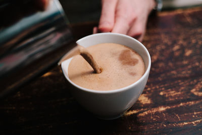 Hand holding coffee cup on table