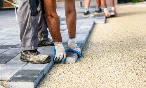 Construction worker arranging paving stones on street