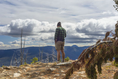 Male hiker on mountain top with dramatic clouds