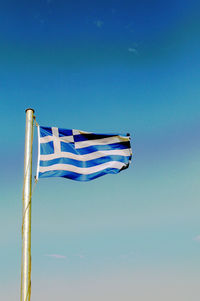 Low angle view of flags against clear blue sky