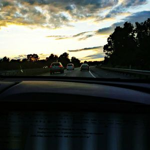 Road passing through forest at sunset