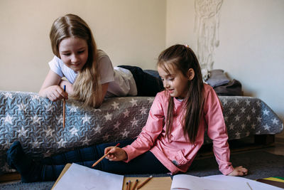 Two girls friends play at home, draw with pencils and felt-tip pens and have fun