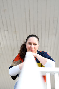 Portrait of smiling woman standing against wall