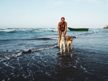 Young woman playing with dogs on shore at beach