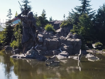 Sculpture by lake against sky