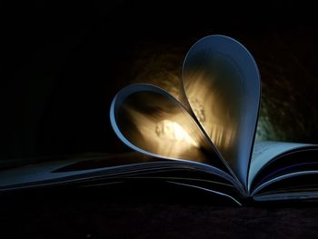 Close-up of heart shape pages on book in dark