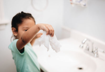 Cute girl washing napkin at sink