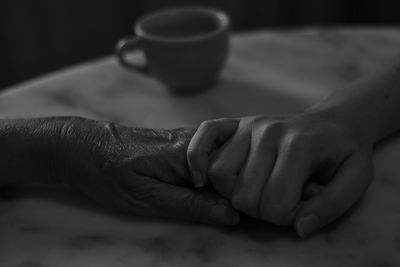 Cropped hands of mother and daughter on table