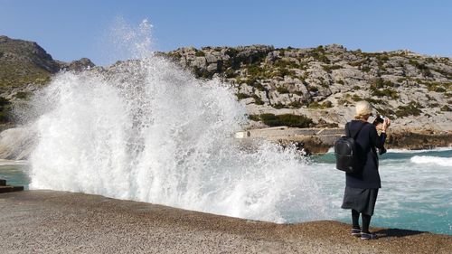 Rear view of woman standing by sea against sky