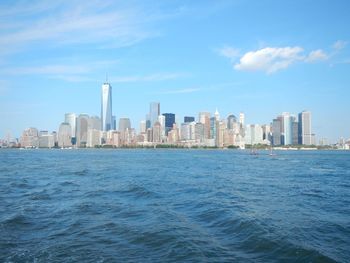 Sea by cityscape against sky