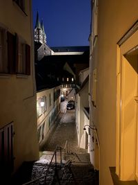 Empty alley amidst buildings in city at night