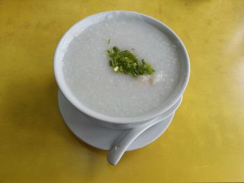 Close-up of fresh congee served in bowl on yellow table