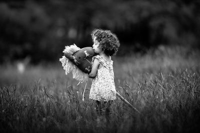 Girl holding toy while standing on field