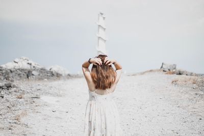 Rear view of woman standing at beach against sky