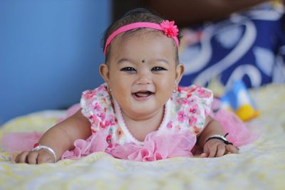 Portrait of smiling baby girl lying on bed at home