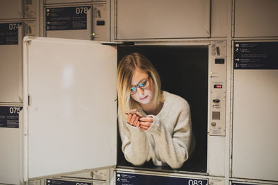 Young woman using phone in locker