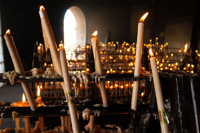 Illuminated candles in temple against building