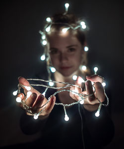 Young woman holding illuminated light bulb