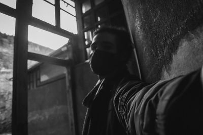 Close-up portrait of man standing by window