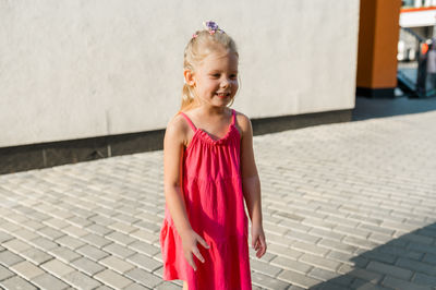 Portrait of young woman standing on footpath