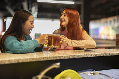 Young women holding glasses of beer at bowling alley