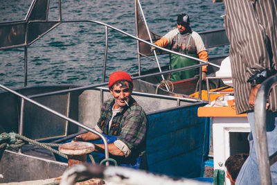 Men sitting on railing by sea