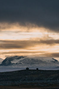 Scenic view of mountains with huts against sky during sunset