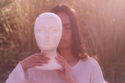 Woman with closed eyes holding statue outdoors