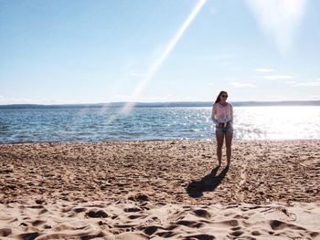 Full length of woman standing on shore at beach against sky