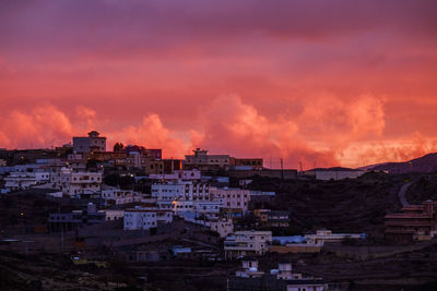 Buildings against cloudy sky during sunset in city