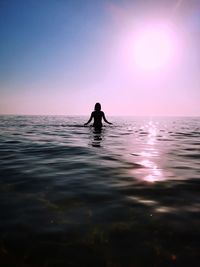 Silhouette man on sea against sky during sunset