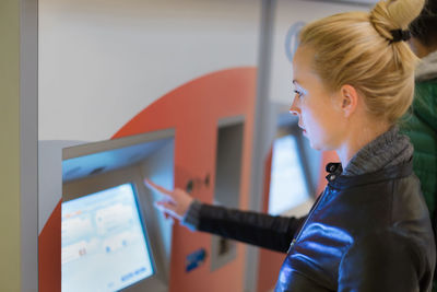 Side view of woman standing by vending machine at station