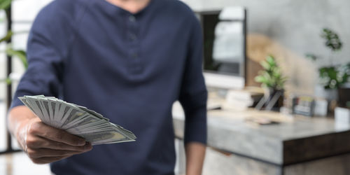 Midsection of man holding paper currency