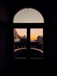 Silhouette buildings against sky seen through window