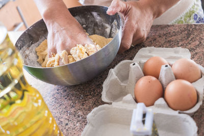 High angle view of woman kneading dough in bowl on kitchen counter