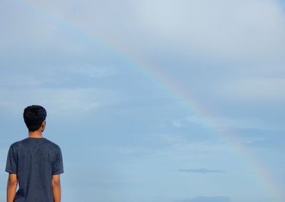 Rear view of man against rainbow in sky