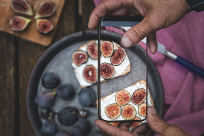 Man hands takes picture of food on the table with the phone. breakfast. sandwich .