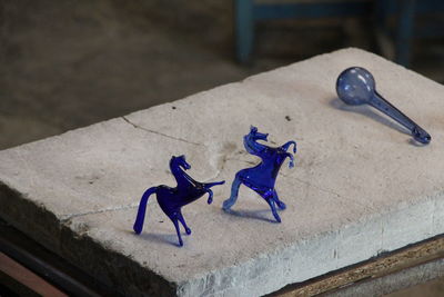 High angle view of glass blue horses on table