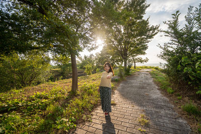 Woman standing on footpath amidst trees