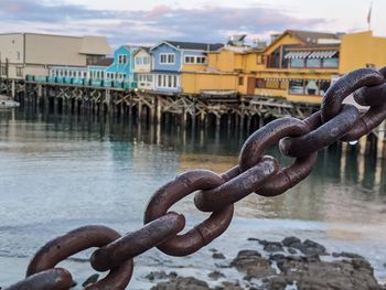 Close-up of chain against sea and buildings