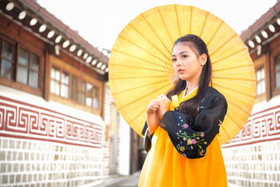 Korean girl wearing a hanbok wearing yellow umbrella. the famous palaces in seoul. 