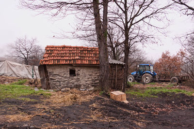 Tractor by cottage against sky