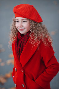 Portrait of young woman standing against wall